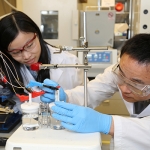 Xueli Zheng, left, and Dr. Bo Zhang set up their device to efficiently split water to store energy as hydrogen. The key is a catalyst made of tungsten, iron and cobalt that is over three times more efficient than the current state-of-the-art. (Photo: Marit Mitchell)