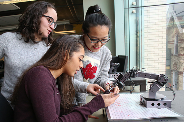 First-year students (from left) Michela Trozzo (Year 1 ECE), Christian Pavlidis (Year 1 CivE) and Elisha Lu (Year 1 ECE) work with a robotic arm in the Systems Control lab. More than 40 per cent of U of T Engineering's first-year students are female, the highest proportion in Ontario. (Credit: Roberta Baker).