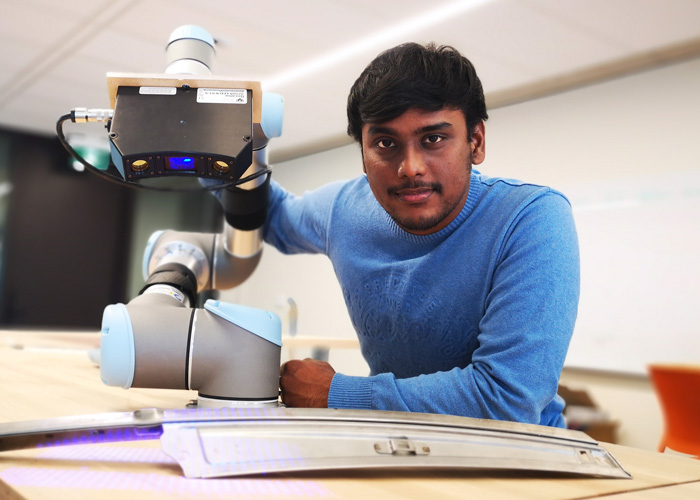 Graduate student Harikrishnan Madhusudanan, who works in the lab of Professor Yu Sun, demonstrates a robotic system that creates 3D digital representations of auto parts, such as this door panel. (Photo: Xingjian Liu)