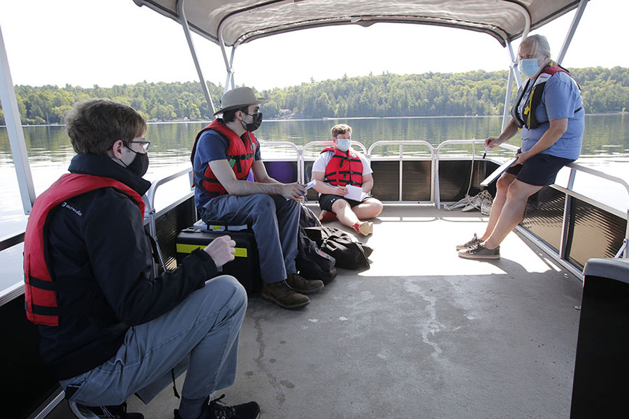 CivMin students listen to Prof. Lesley Warren (right) discuss water sample collection methods, while aboard the boat Sir Veyor on Gull Lake, as part of their studies at U of T Survey Camp on Sunday, August 15, 2021. (Photo: Phill Snel)