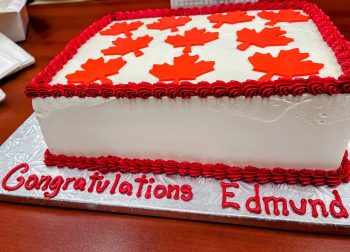 White cake with red icing that says, "Congratulations Edmund"