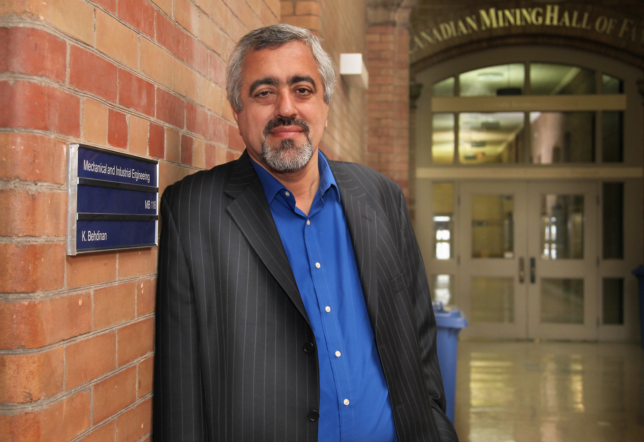 A man stands next to a brick wall.