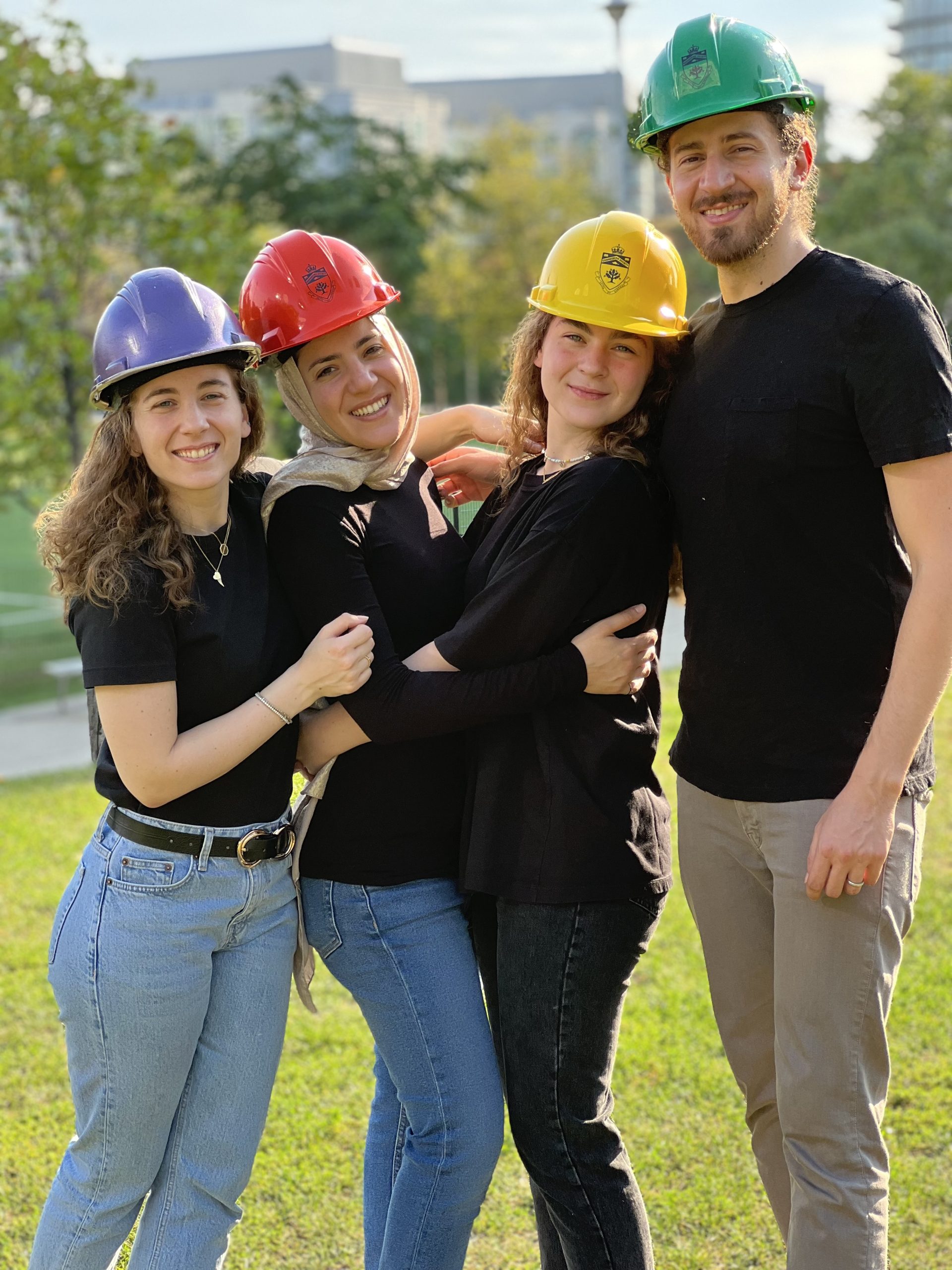 From left to right: Dareen Kutob wears a purple hard hat, Layan Kutob wears a purple hard hat, Taleen Kutob wears a yellow hard hat and Kazem Kutob wears a green hard hat. The four siblings pose together in an outdoor setting.