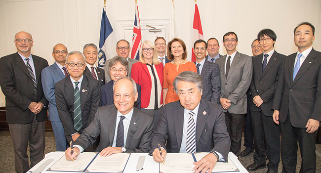 U of T President Meric Gertler, seated centre left, and Shigeru Sasaki, CEO of Fujitsu Laboratories, seated centre right, sign a memorandum of understanding. This marks the first R&D centre opened in Canada by Fujitsu Laboratories, a major engine of research and development in the world’s leading innovation clusters such as Silicon Valley, London and Shanghai. (Credit: Lisa Lighbourn)