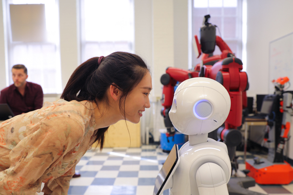 Xinyi Zhang (MIE MASc candidate) interacts with Pepper the robot. (Credit: Liz Do)
