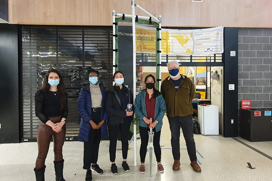 Left to right: Tatiana Estevez (Permalution), Valerie Ajayi (MechE 2T1 + PEY), Kelly Chu (MechE 2T1 + PEY), Eva Liu (MechE 2T1 + PEY) in phone picture, Alyson Wong (MechE 2T1 + PEY) and Professor Markus Bussmann (Chair, MIE) stand next to a prototype fog harvester in the student arena within the Myhal Centre for Engineering Innovation & Entrepreneurship. (Photo submitted)