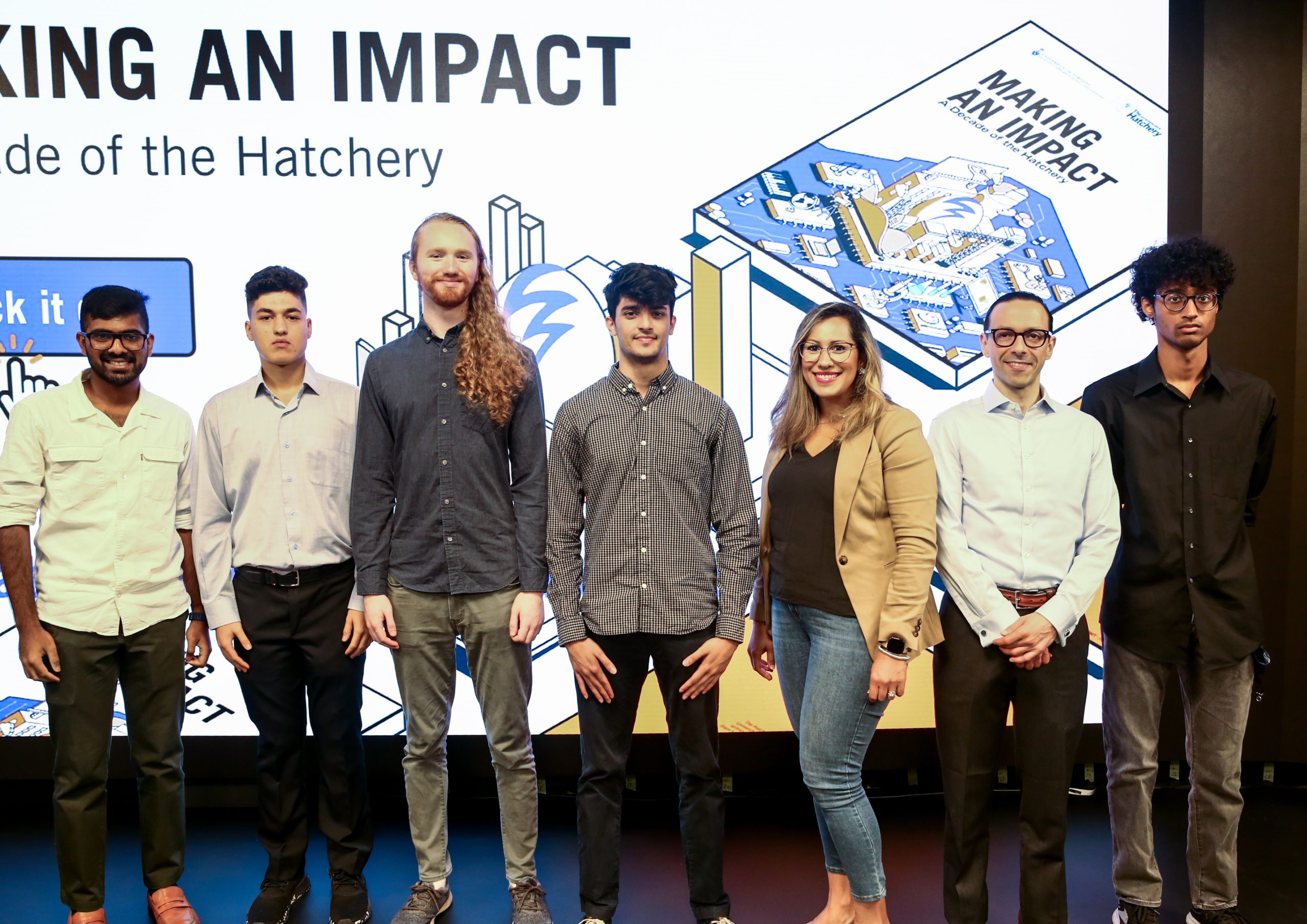 A group of students stand in front of a screen