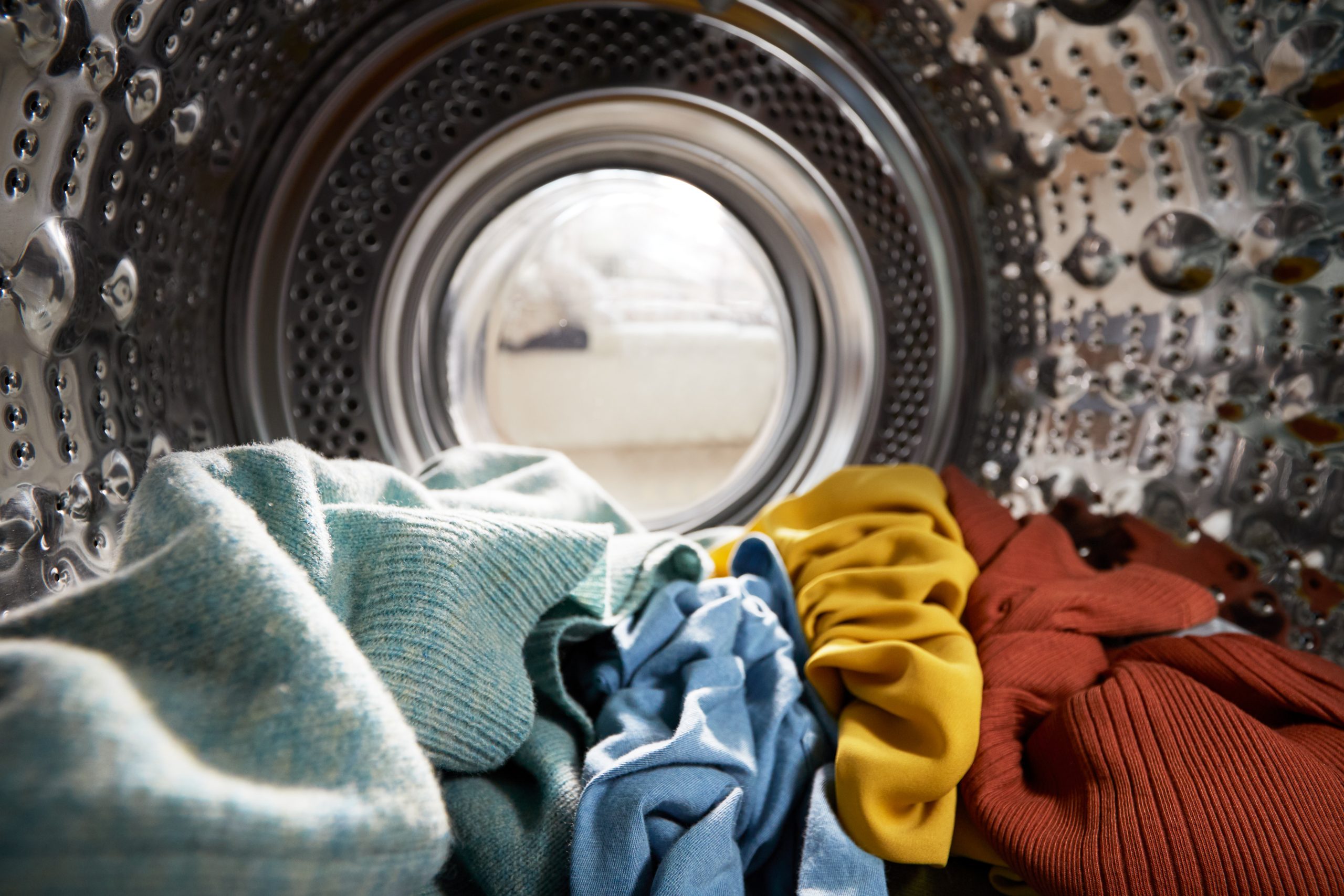 View from inside a washing machine filled with colourful laundry