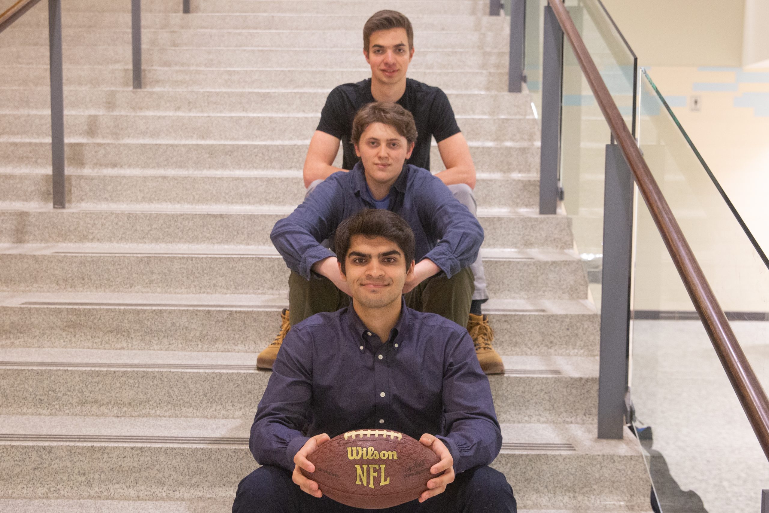 Three men sit, descending on a stairwell.