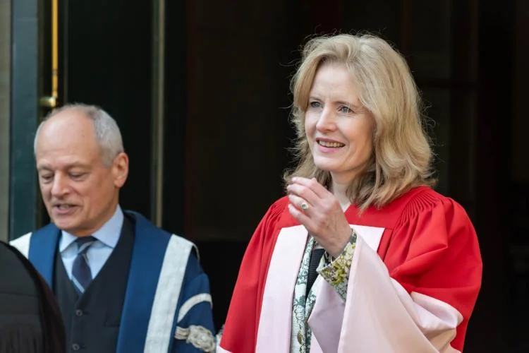 Claire Kennedy, who is on the right, exits U of T's Simcoe Hall on her way to receive her honorary degree. To her left is U of T President Meric Gertler.