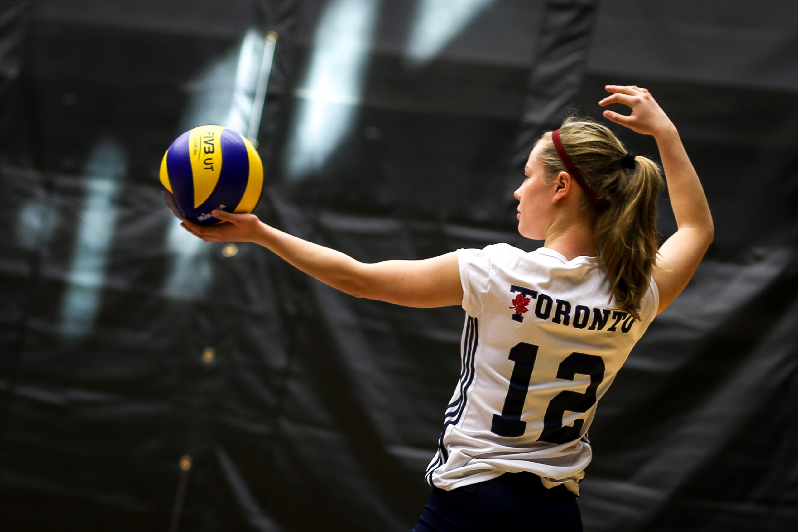 A women volleyball player prepares to spike a ball.