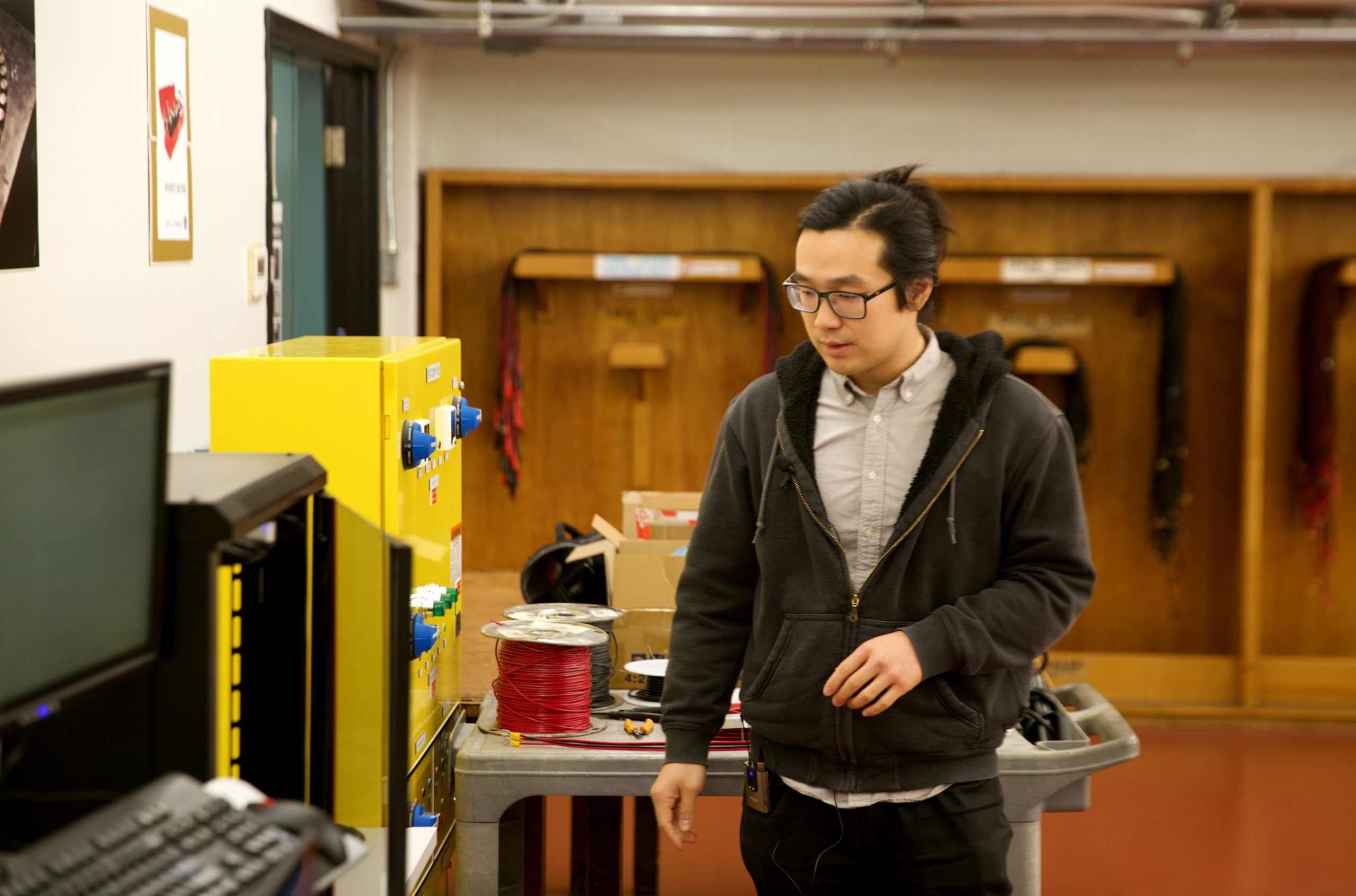 Dr. Zhe Gong walks walks past equipment that make up the electric vehicle lab station.