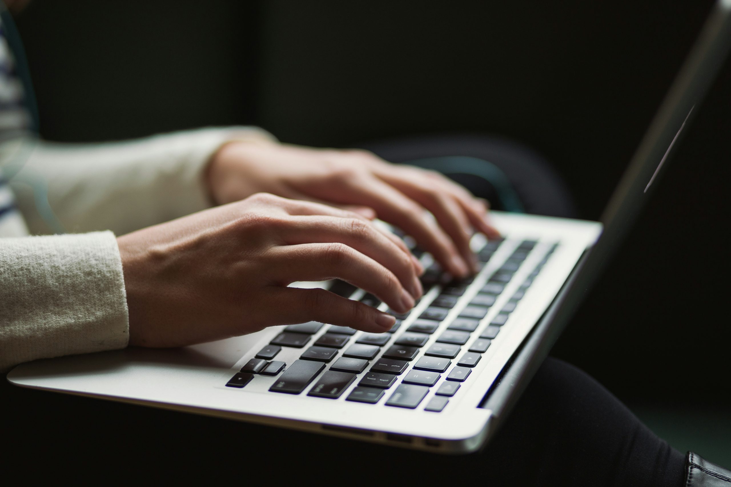 A person has their fingers positioned over a laptop keyboard.