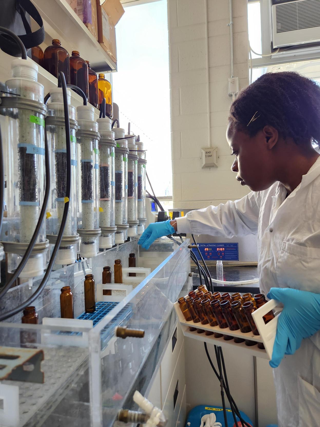 Researcher wearing white lab coat and blue gloves works with lab equipment. 