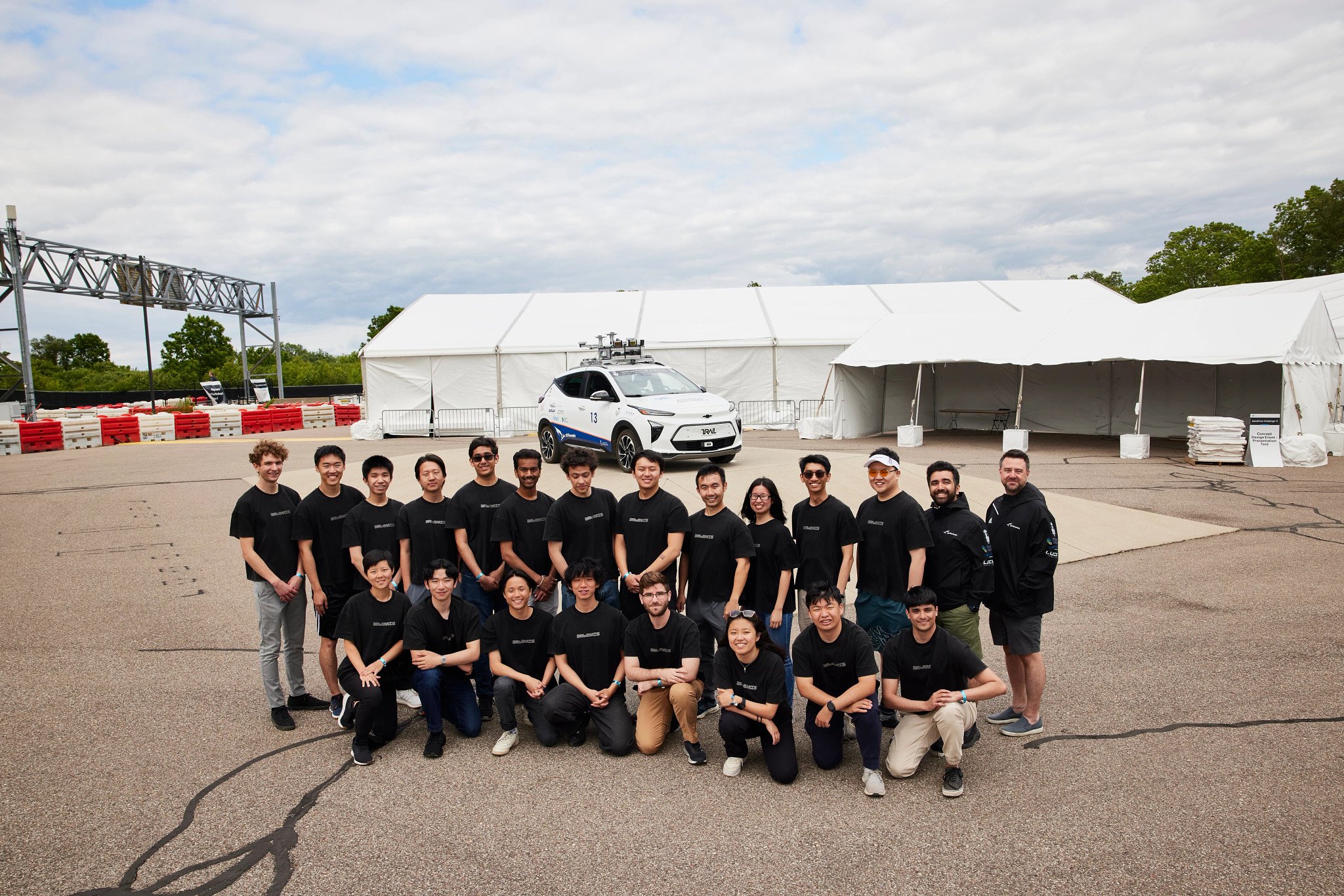 The aUToronto pose at the Mcity testing facility with their autonomous vehicle in the background.