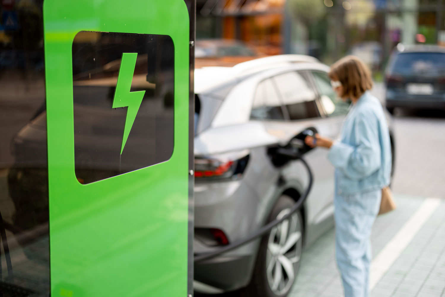 woman-charging-her-car-on-public-fast-charger-2023-11-27-04-51-43-utc_1500x1000