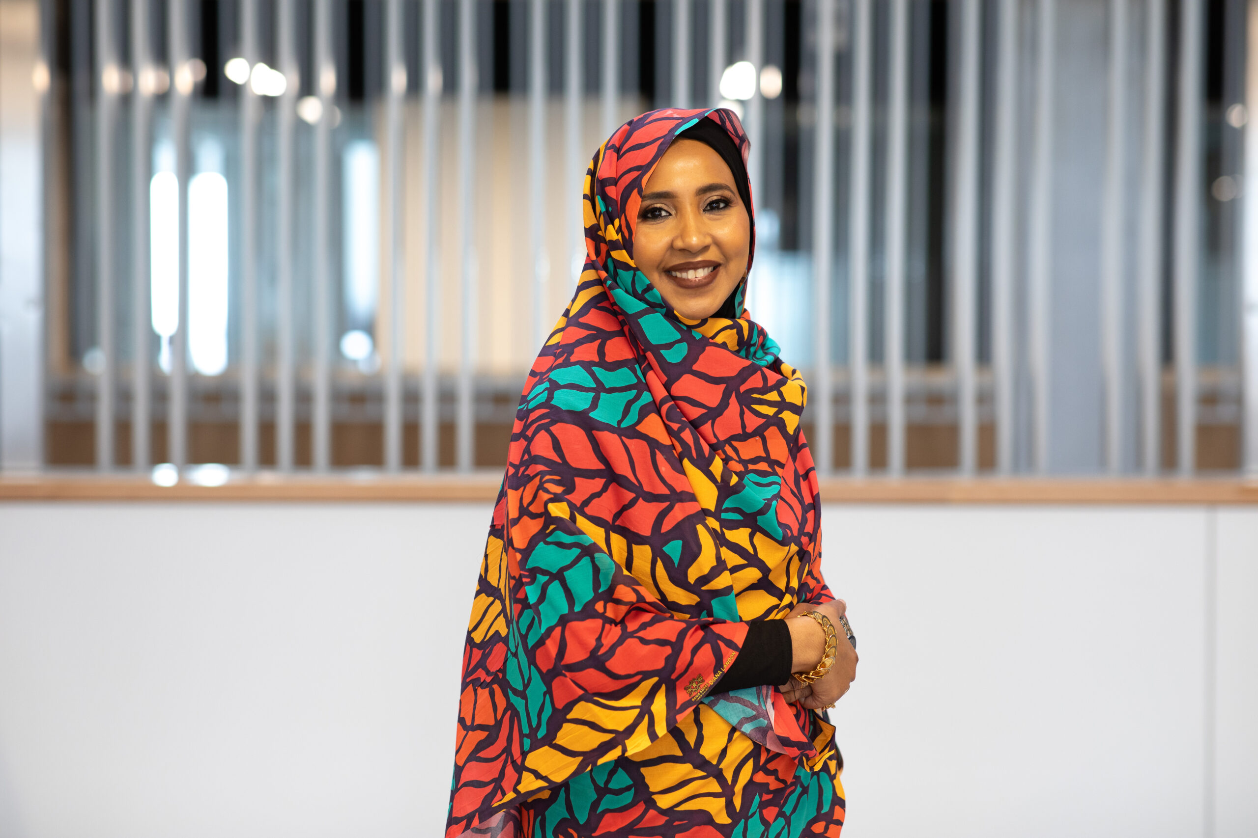 Mai Ali wears the Toub, a traditional garment from Sudan. The black-outlined pattern is filled with red, orange and green.