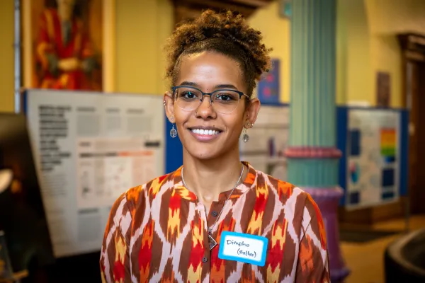 Dimple stands in front of poster presentation displays, smiling at the camera