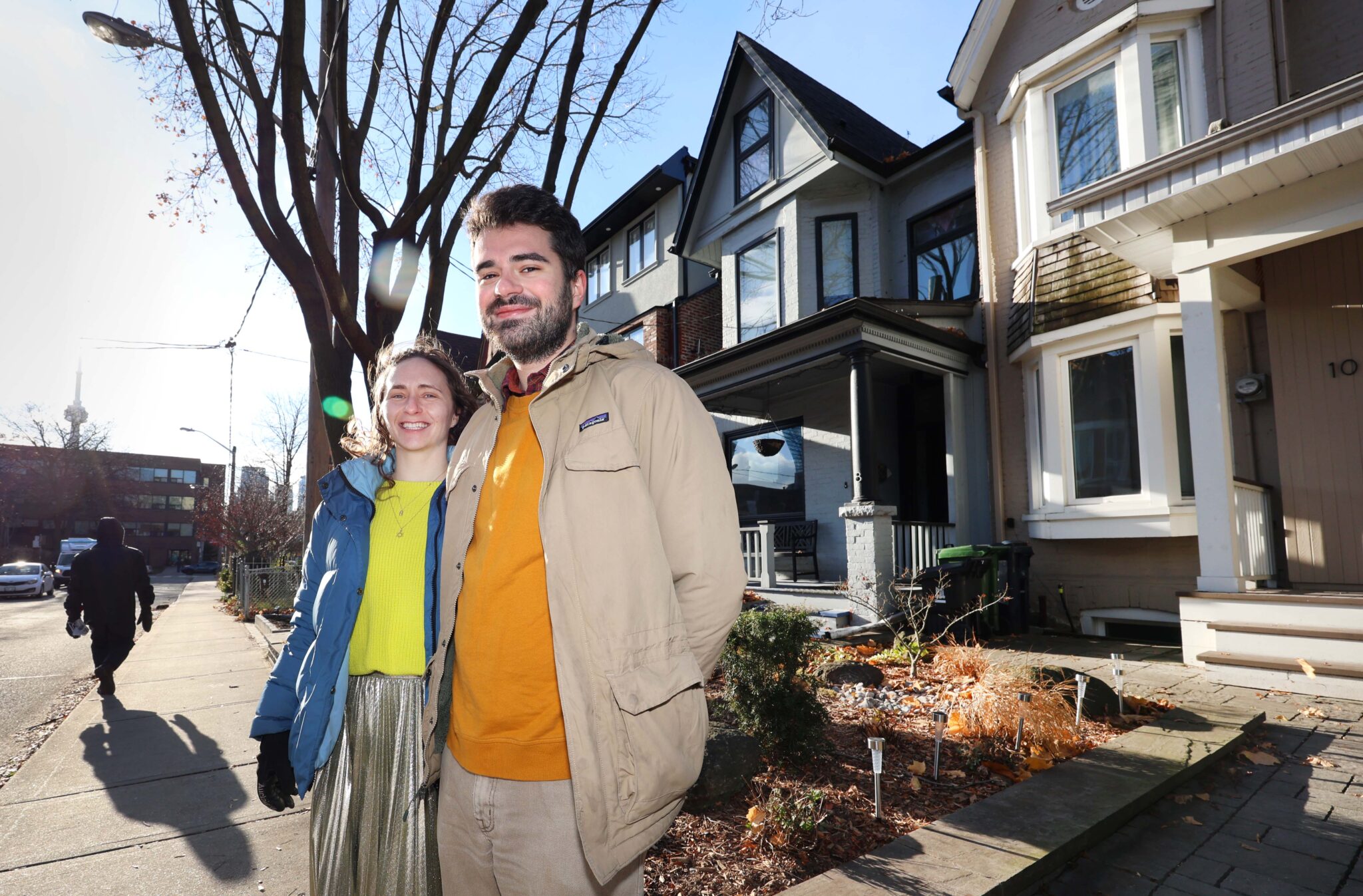 Saxe and Olson stand on the sidewalk of a street lined with houses