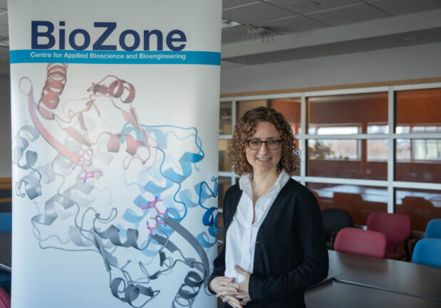 Emma Master stands in a classroom beside a banner that reads BioZone.