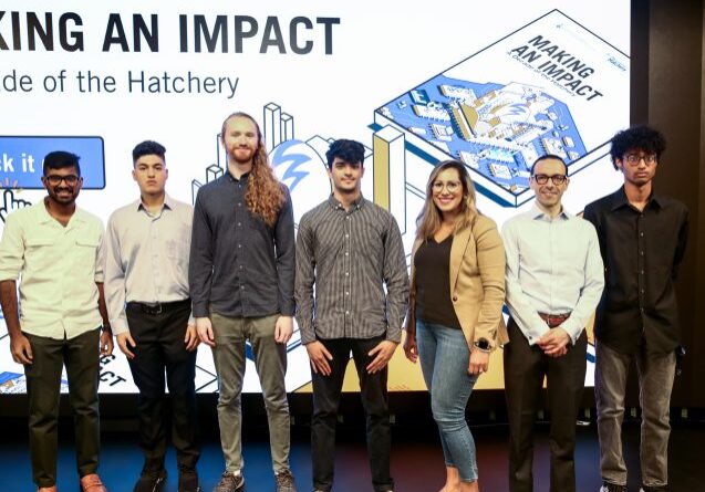 A group of students stand in front of a screen