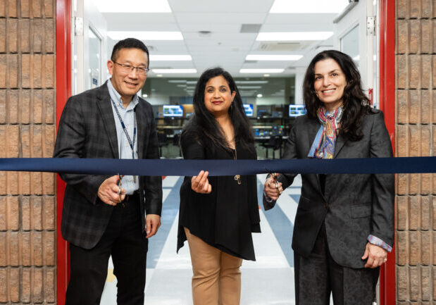 Chris Yip, Deepa Kundur and Marie Hattar, stand before a ribbon. Chris and Marie hold scissors to the ribbon.