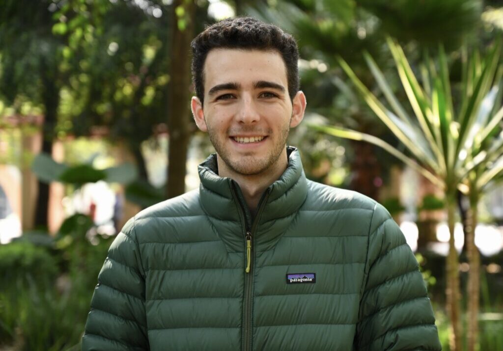 Headshot of Martin Staadecker, wearing a green puffer jacket, with trees in the background.