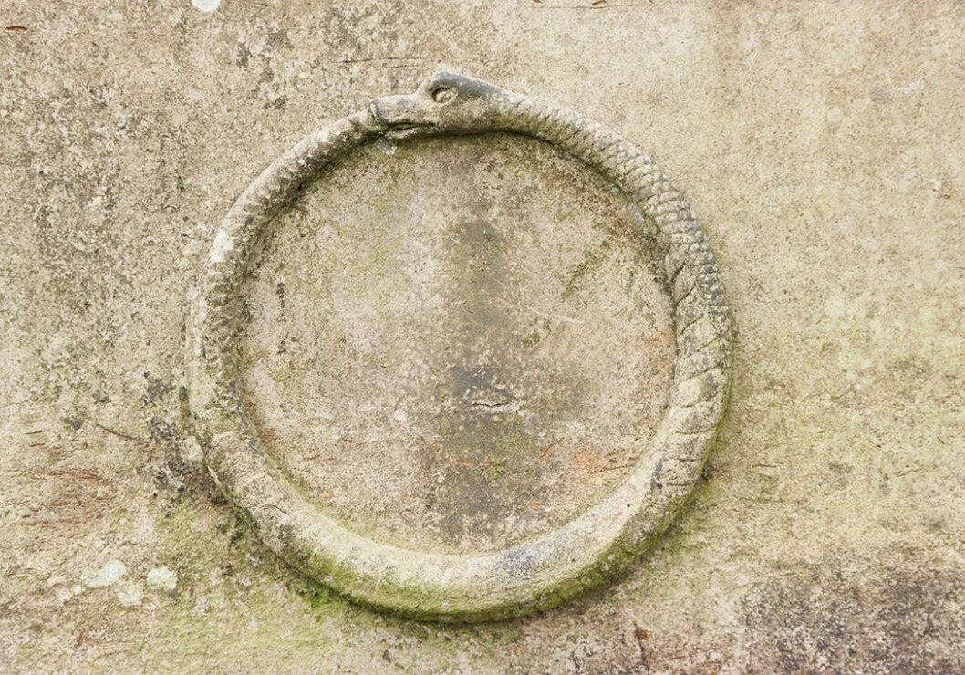 An ouroboros (snake eating its own tail) carving in stone.