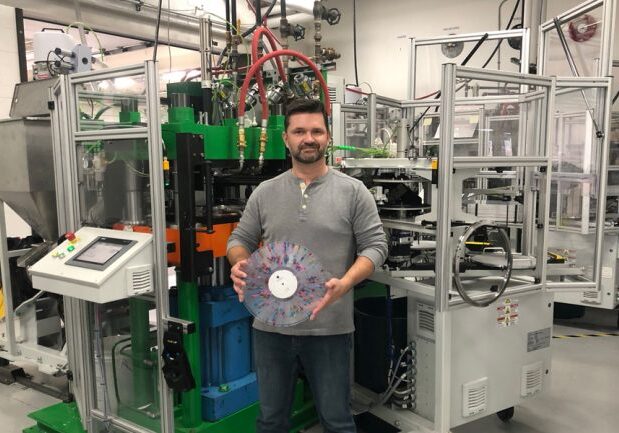 Rob Brown (MechE 0T0), chief operating officer of Viryl Technologies, holds up a “splatter” record made on the company’s LiteTone vinyl press. Viryl Technologies is one of only two firms worldwide that produce such machines. (Photo: Doug Chappell)
