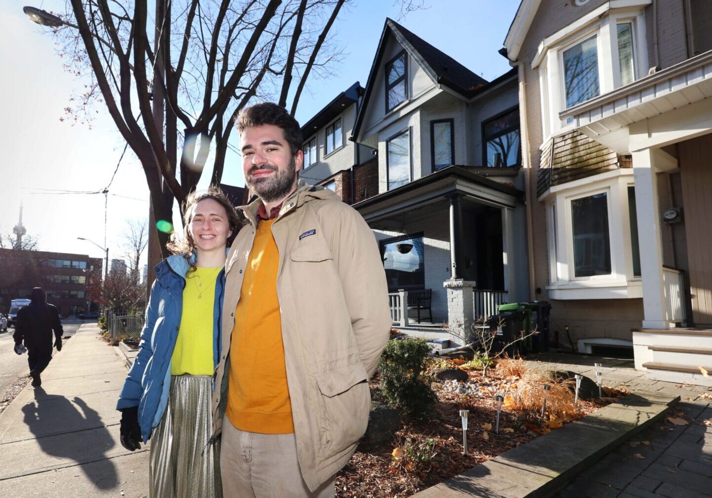 Saxe and Olson stand on the sidewalk of a street lined with houses