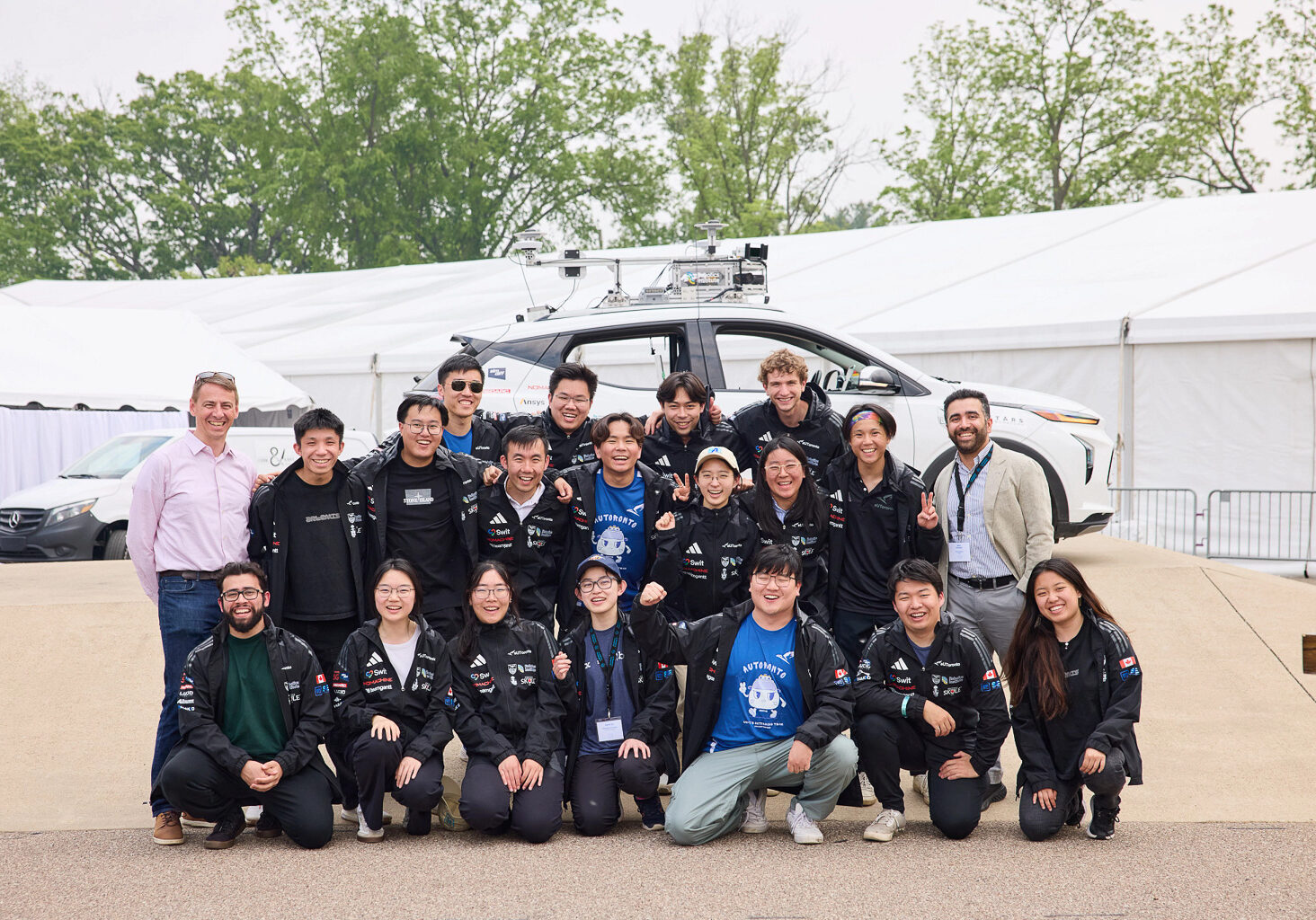 The team stands in front of the autonomous car in Michigan