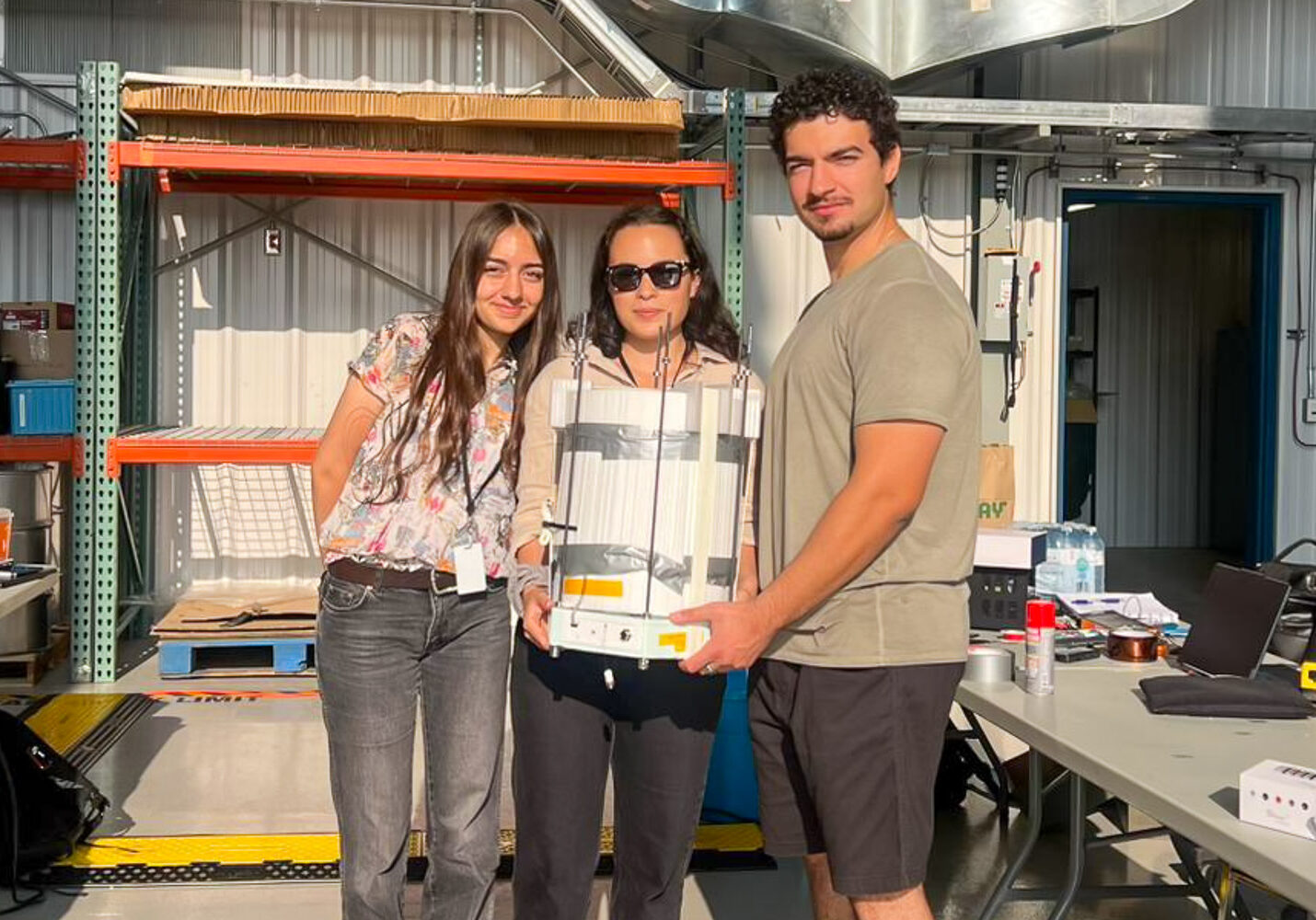 Begum Yilmaz, Katarina Poffley and Emre Yilmaz hold their payload at the Canadian Space Agency’s Timmins stratospheric balloon base.